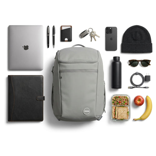 Gray backpack with various items including a laptop, snacks, and technology gadgets on a white background
