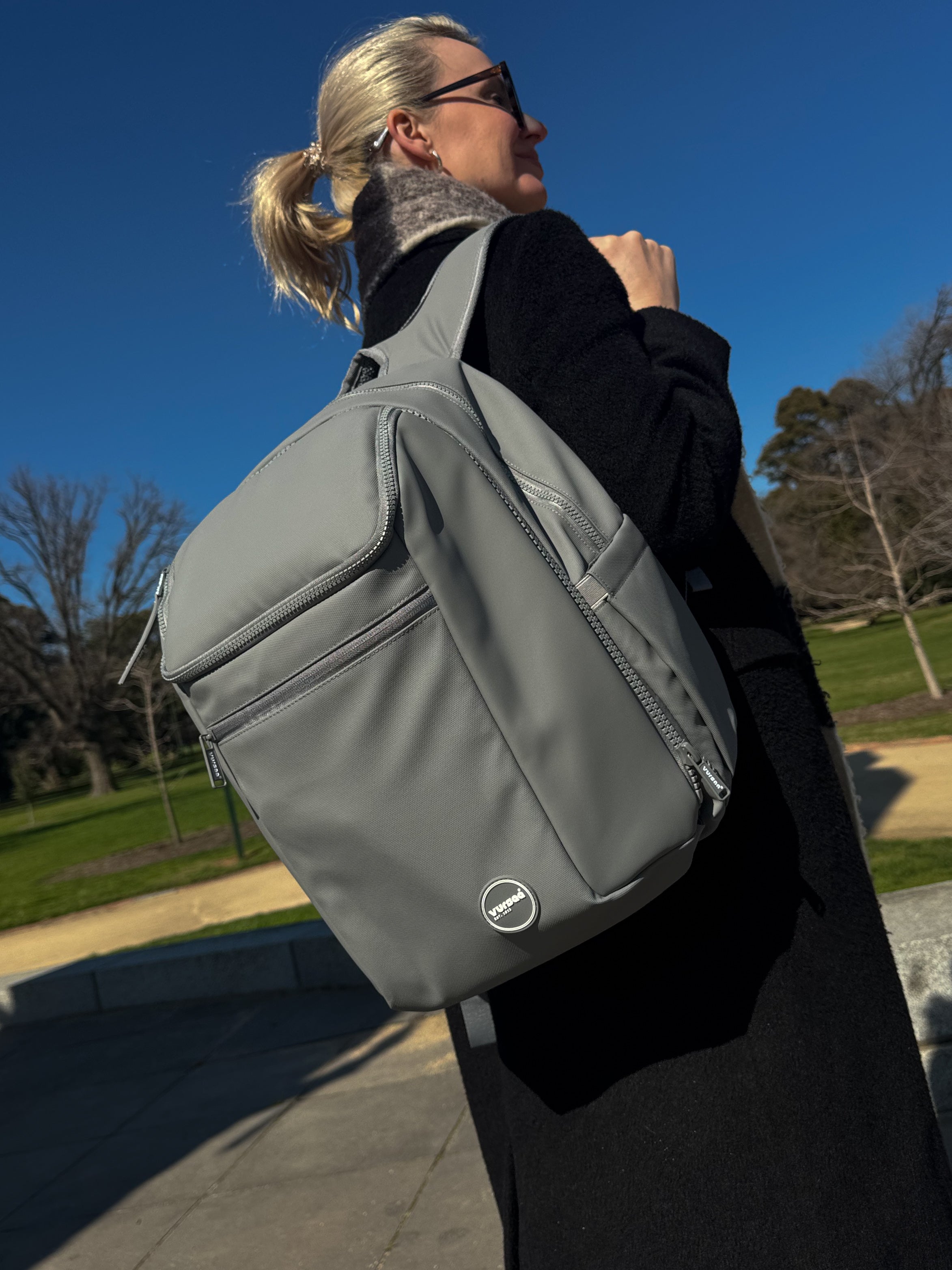 Person wearing a gray modular backpack outdoors on a clear day