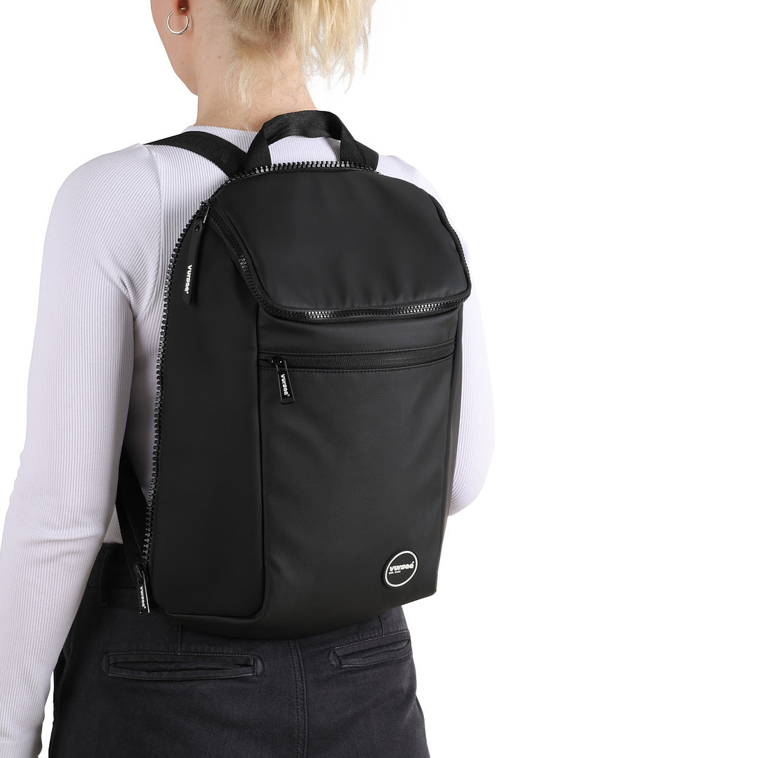 Person wearing a black modular backpack with a visible brand logo on a white background. Person only wearing insulated front section of 3 in1 backpack. 